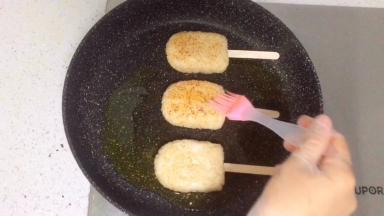 把饭团放入平底锅，再刷一层酱油。
