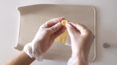 用裱花嘴圆形的一端在芝士片上压出小圆片，贴在火腿片上。