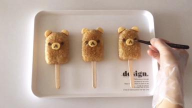 椭圆芝士片放在饭团中间，用海苔剪出眼睛、鼻子和嘴，借助镊子放到相应的位置上，完成！