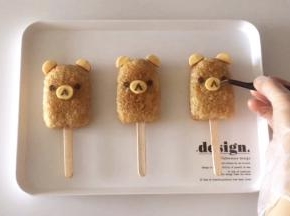 椭圆芝士片放在饭团中间，用海苔剪出眼睛、鼻子和嘴，借助镊子放到相应的位置上，完成！