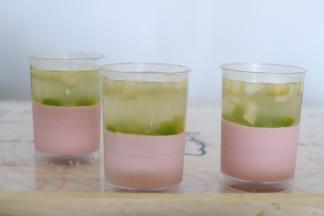 放凉后的镜面糖水加入到粉红色的慕斯杯内，随意放入李子粒和水蜜桃粒，也可以放上一粒糖渍李子增加口感和美感。