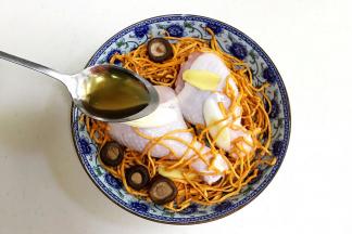 底下先放些葱段，摆上鸡腿，放上虫草花和泡发好的香菇、姜片，淋上一勺料酒。