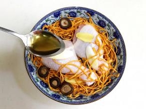 底下先放些葱段，摆上鸡腿，放上虫草花和泡发好的香菇、姜片，淋上一勺料酒。