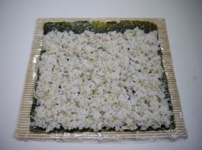 带上一次性手套，手套上稍微抹一点点油，取210g藜麦饭，均匀地铺在海苔上，不要铺满，留出一个手指的宽度，寿司的卷帘要用保鲜膜包起来，这样就不会沾，而且卷起来也很轻松。