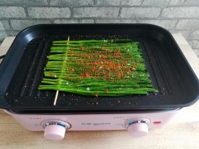 在烤好的韭菜上撒适量的孜然粉，盐和辣椒粉