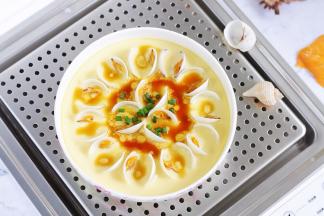 往蒸好的蛤蜊蛋羹中淋入调料汁，撒上葱花。