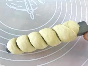 将面团卷在学厨圆形面包管上，卷的时候要将起点的面团压在里面，然后顺时针旋转卷起，收口处面团捏紧
