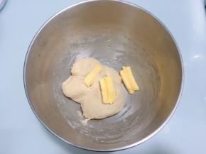 面团表面揉至表面光滑后加入软化的黄油，开低档揉至黄油完全融合于面团