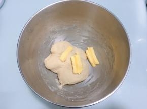 面团表面揉至表面光滑后加入软化的黄油，开低档揉至黄油完全融合于面团
