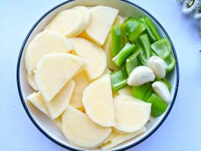 土豆去皮切片，泡水10分钟清洗掉淀粉。青椒切小块，大蒜去皮拍扁。