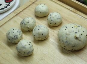 发酵好的面团按压排气，先分出6个35g的小面团，剩下的作为大面团，将它们都滚圆之后盖上保鲜膜松弛15分钟。