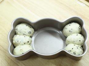 松弛好的小面团压扁后滚圆，再整形成椭圆形。小面团放在学厨糖果型模具的两边。