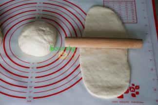 醒好的面团，取一块，用擀面杖擀成长条面片，面片的宽度要与土司模具的宽度一致。