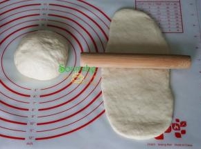 醒好的面团，取一块，用擀面杖擀成长条面片，面片的宽度要与土司模具的宽度一致。
