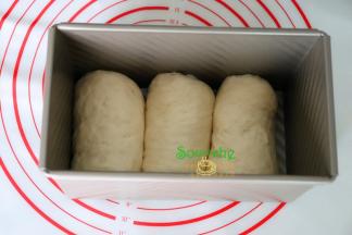 卷好的面团收口朝下，放入到吐司内，接着第二、三个也按照这方法依次将面包胚放入土司模具里。