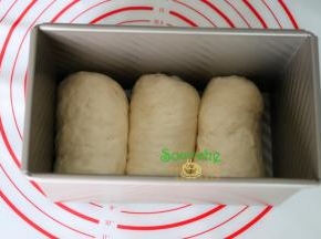 卷好的面团收口朝下，放入到吐司内，接着第二、三个也按照这方法依次将面包胚放入土司模具里。