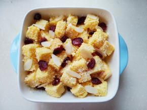 吐司放入碗中，撒上椰蓉，加入蔓越莓，加入杏仁片。