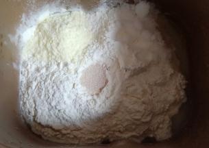 加入中筋面粉，奶粉和糖对角放，中间挖个洞放入酵母。