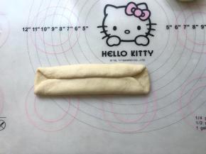 之后将面团翻转个面，光滑的一面朝下，将两侧面团像中间对折，之后用擀面杖轻轻擀宽一些