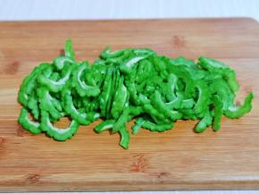 首先将苦瓜洗干净，对半切，把瓤挖出来，再切片。