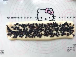 再用擀面杖轻轻擀宽一点，撒上一层蜜红豆