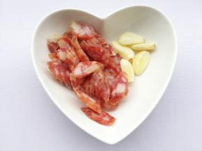 腊肠切斜片，大蒜去皮拍扁。