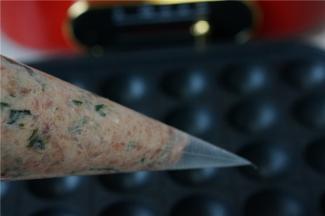 多用锅放上丸子烤盘，然后刷上一层薄油，预热好之后转中火，将拌好的肉馅装至裱花袋里，然后再剪一个大口。