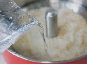 然后将提篮装回至锅里，并加入清水，用水量跟平常的水量一样，都是满至米粒表面就可以。