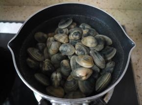 锅中烧水，水开了之后把蛤蜊倒进去，加2片姜片去腥，煮至蛤蜊开口。