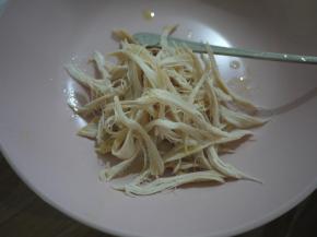 鸡肉煮熟后捞出稍微冷却，然后把鸡肉撕成细条备用。鸡皮是不要的。