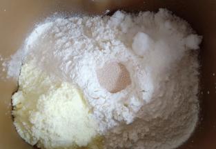 放入500克中筋面粉，对角放奶粉和糖，中间挖个洞放入酵母。