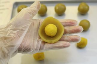 取15克的白莲蓉馅压成薄片，包上10克的奶黄馅。