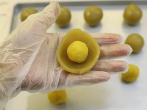 取15克的白莲蓉馅压成薄片，包上10克的奶黄馅。