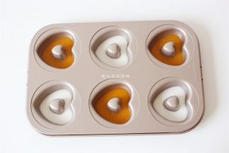 爱心模具抹上油，将芒果口味和椰浆口味的凉糕液倒入孔内，放入冰箱冷藏凝固。