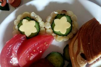 把花形芝士片和黄瓜片摆在玉米上做装饰