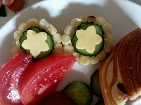 把花形芝士片和黄瓜片摆在玉米上做装饰