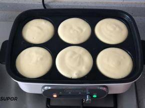 多功能锅用六圆盘预热后，刷一层油，往圆盘里舀入一大勺面糊。用不粘平底锅也可以，面糊会自然形成圆形。