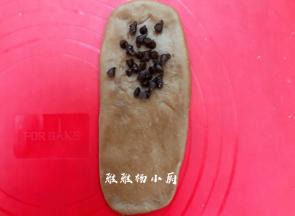 取一个小面团，把小面团擀成椭圆形，借助刮板把面团翻面，铺上巧克力豆
