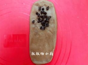 取一个小面团，把小面团擀成椭圆形，借助刮板把面团翻面，铺上巧克力豆