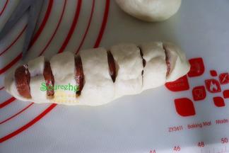 卷起的热狗面包胚，用剪刀剪断热狗及表面的面皮，底部的面皮不要断。