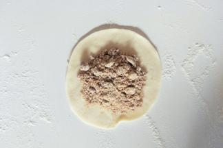 取一个小面团擀成中间厚周边薄的面皮，包入红糖馅。