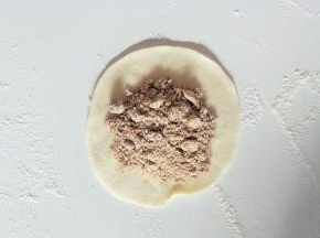 取一个小面团擀成中间厚周边薄的面皮，包入红糖馅。
