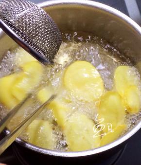 油锅继续烧热，至五、六成热时，将土豆片放入复炸