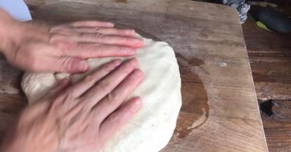 在案板上抹上少许油，放入面团，拍打排气