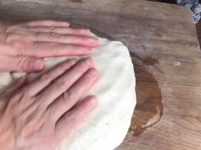 在案板上抹上少许油，放入面团，拍打排气