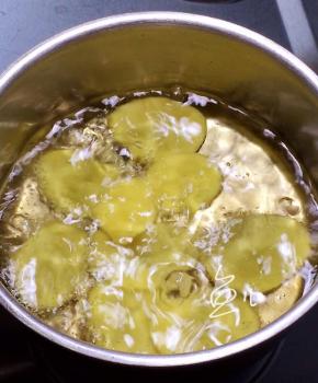 油锅烧至四成热，将土豆片一片一片放入油锅中