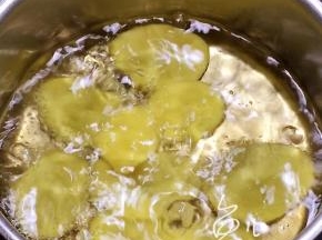 油锅烧至四成热，将土豆片一片一片放入油锅中