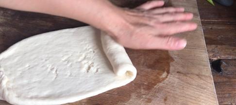 松弛好的面团擀皮牛舌状，在一头卷起成卷