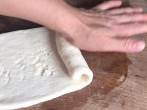 松弛好的面团擀皮牛舌状，在一头卷起成卷