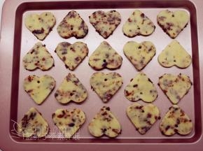 用小吸管在心型饼干上戳出一个洞，再一一摆放到学厨烤盘中。